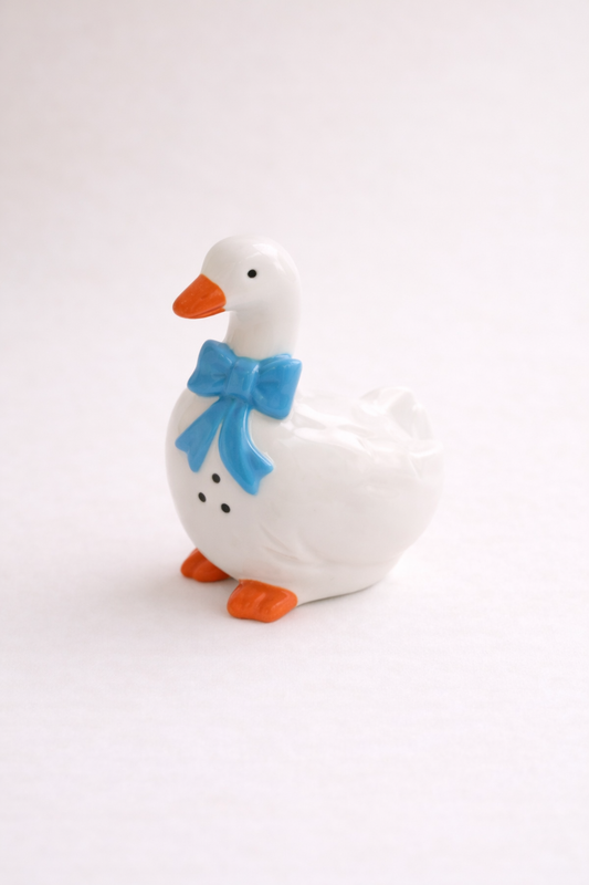 White goose figurine with a blue bow on a white background