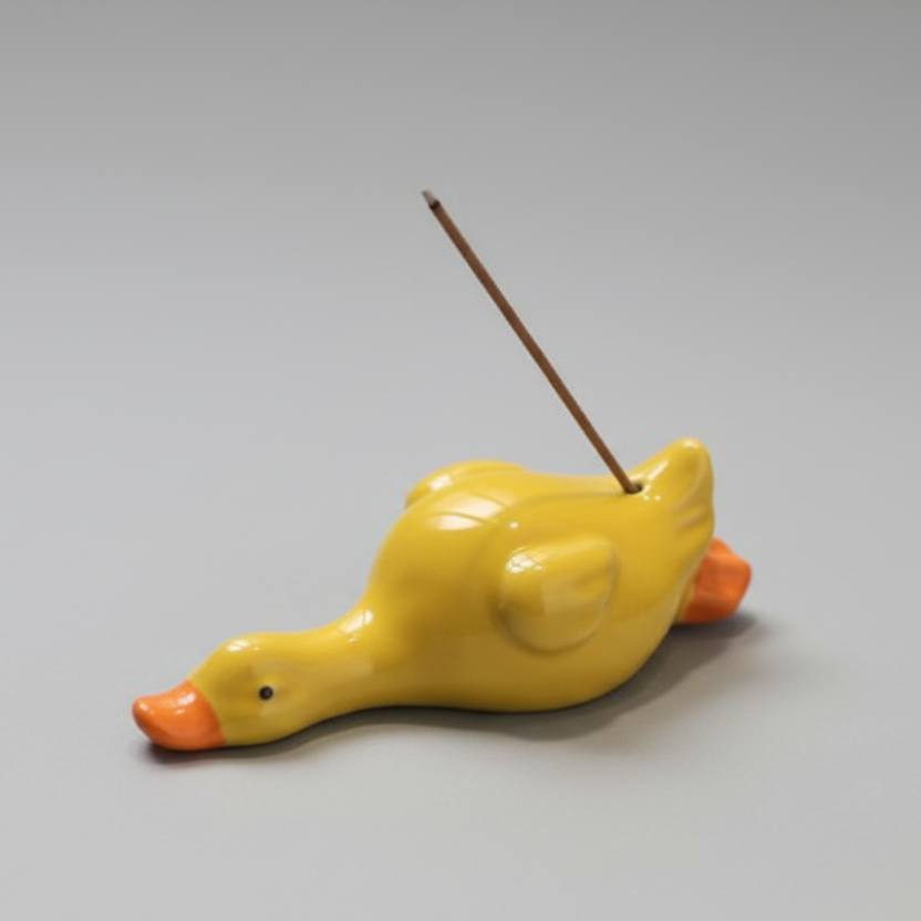 Yellow ceramic incense holder with orange accents on a white surface