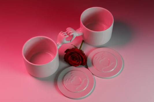 Two porcelain cups with a heart-shaped handle connecting them, against a black background.