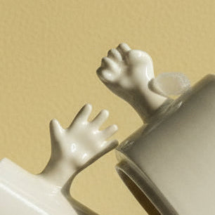 Three porcelain cups representing the classic rock–paper–scissors gestures, arranged as an interactive set that explores play, communication, and everyday ritual through ceramic form.